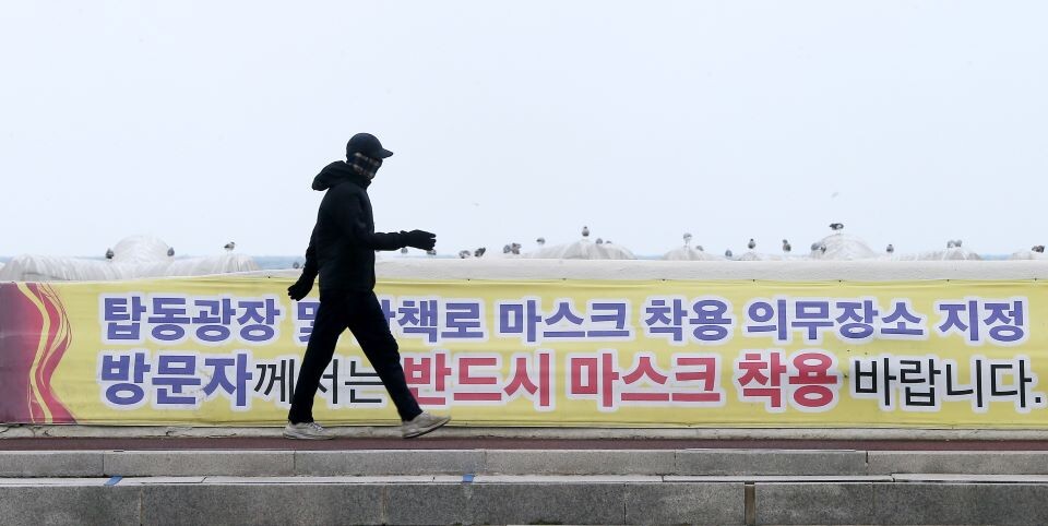 12일 전국적으로 신종 코로나바이러스 감염증(코로나19) 확산세가 이어지는 가운데 제주시 건입동 탑동광장에서 한 도민이 마스크 착용을 당부하는 현수막 옆을 걷고 있다. 연합뉴스