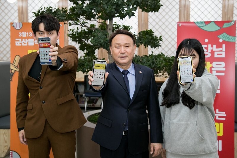 강임준(가운데) 군산시장이 휴대전화를 통해 군산시가 내놓은 배달앱 ‘배달의 명수’를 선보이고 있다. 군산시 제공