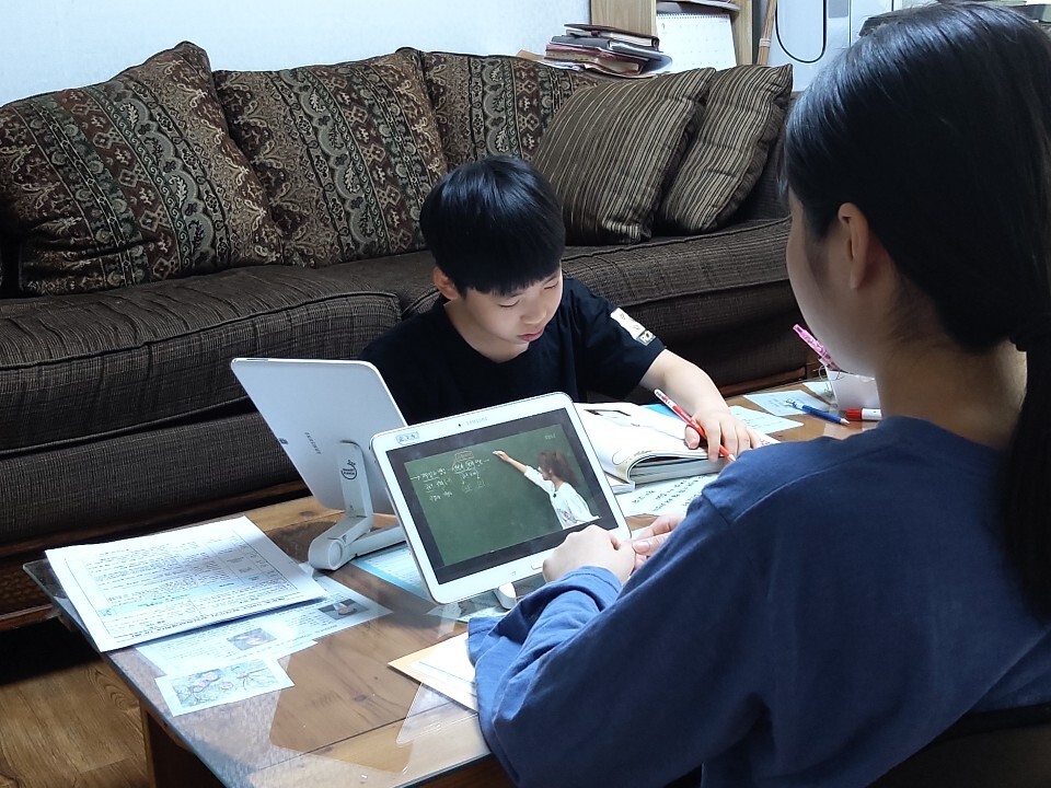 집 거실에 중학교 2학년과 초등학교 5학년과의 통합교실이 마련됐다. 마주 앉아 수업 중인 김하원 양(오른쪽)과 신형 남매. 독자 제공