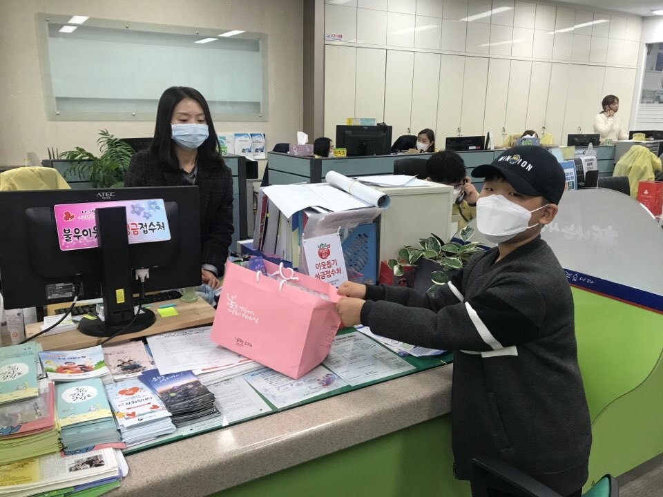 지난 3월 부산 사상구 학장동사무소에 초등학생이 약국에서 줄을 서서 구매한 마스크와 동전 용돈을 전달하고 있다. 학장동사무소 제공