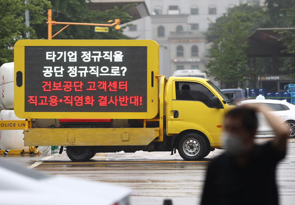 18일 건강보험공단 제3차 사무논의협의회가 열리는 서울 여의도 한 호텔 앞에 주차된 건강보험공단 직원들의 시위트럭에 고객센터 직원 직고용 반대 메시지가 적혀 있다. 연합뉴스