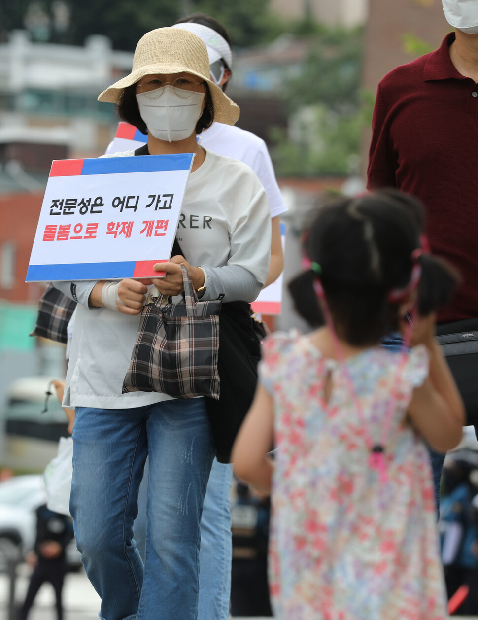 초등학교 입학 나이를 만 5살로 낮추는 교육부 학제 개편 추진에 반발하는 손팻말을 든 한 참가자 옆으로 어린이가 지나가고 있다. 김혜윤 기자