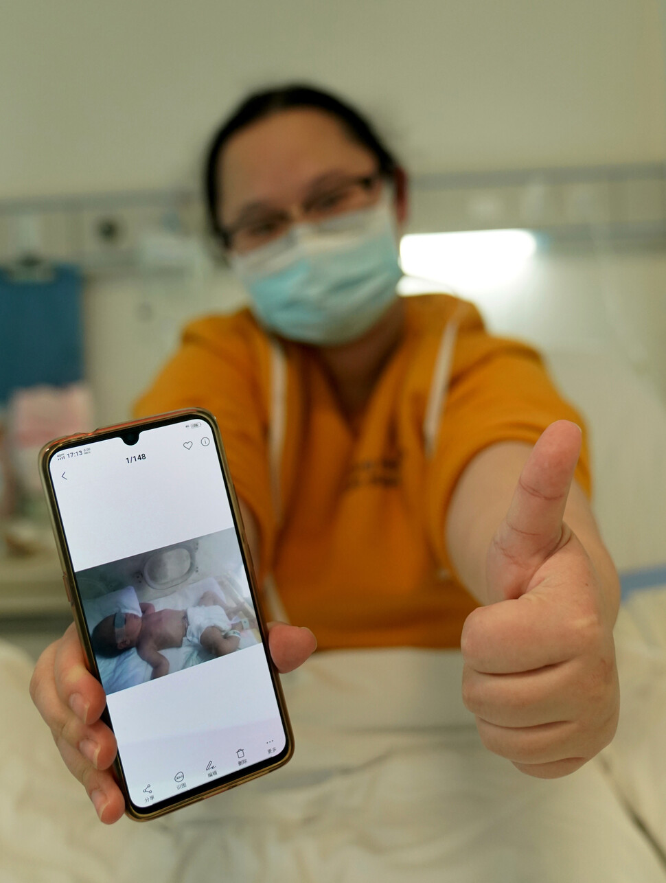 2월18일 우한의 한 병원에서 코로나19로 투병 중인 한 여성이 병상에서 낳은 아기 사진을 보여주고 있다. 아기는 건강 상태가 양호하다.