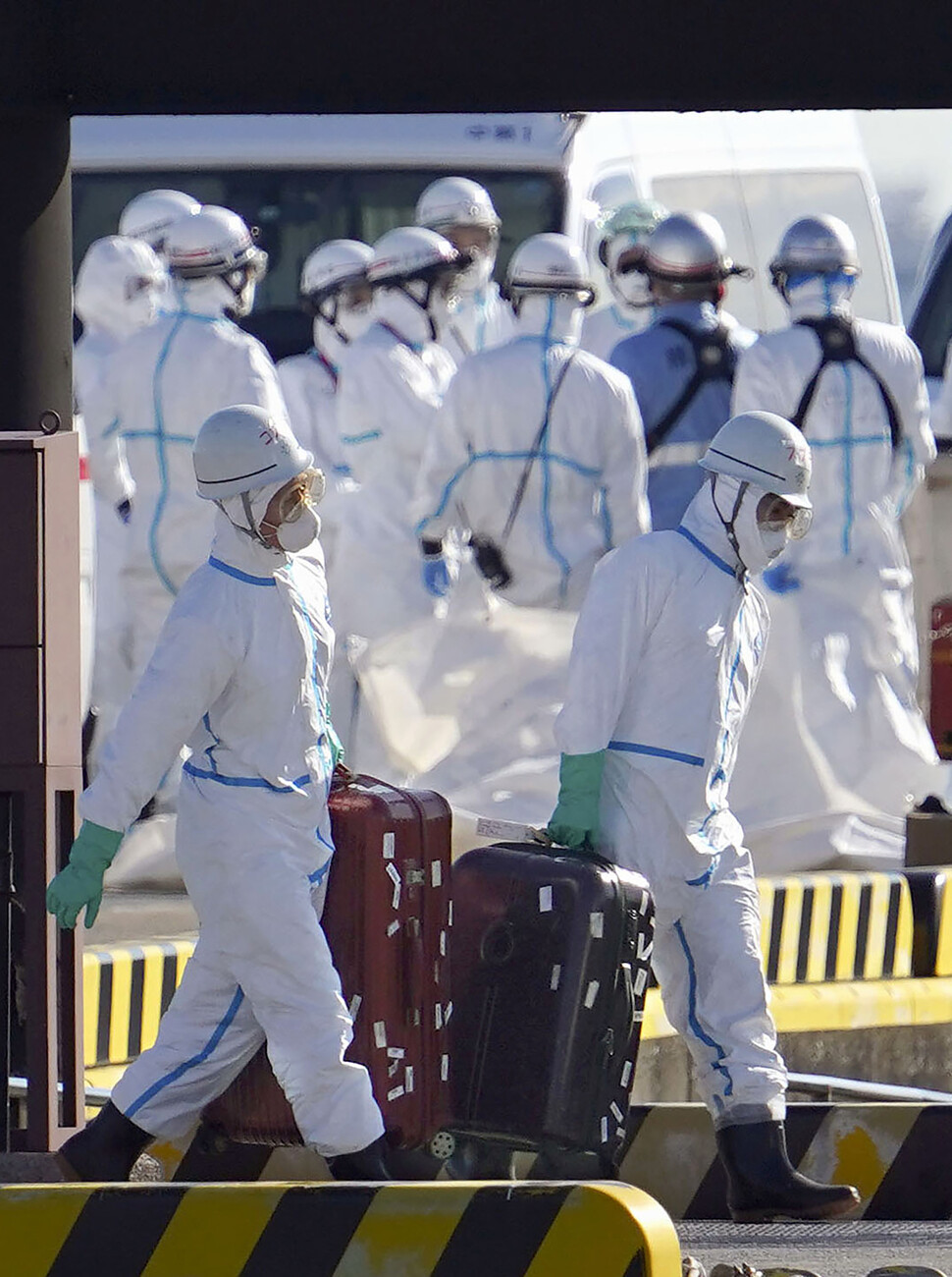 5일 일본 가나가와현 요코하마항에서 흰색 방호복을 입은 일본 의료 관계자들이 신종 코로나바이러스 감염증 환자가 10명 새로 나온 크루즈선 탑승자들의 짐을 옮기고 있다. 요코하마/교도 연합뉴스