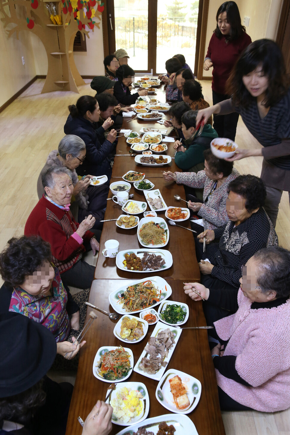 일본군 `위안부' 피해자 길원옥(왼쪽줄 앞에서 둘째부터)·김복동 할머니와 기지촌 할머니들이 2014년 1월 24일 낮 경기 안성시 금광면 한국정신대문제대책협의회 평화와 치유가 만나는 집(쉼터)에서 만나 함께 점심을 나누고 있다. 오른쪽 뒤에 선 이가 윤미향 전 정의기억연대 이사장. 안성/이정아 기자