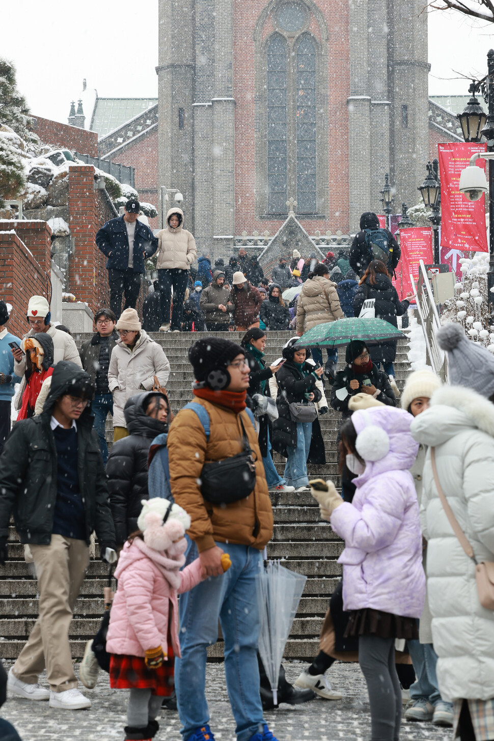 25일 오전 서울 명동성당에서 관광객들이 내리는 눈을 맞고 있다. 김혜윤 기자