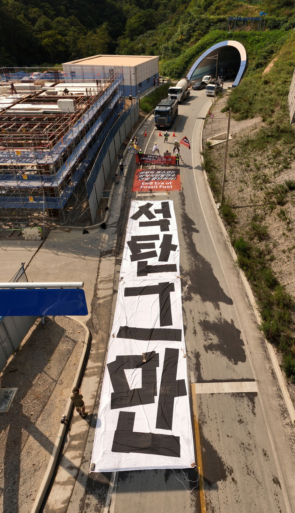 환경단체 회원들이 삼척석탄화력발전소 앞에서 ‘석탄 그만’이라고 적힌 대형펼침막을 바닥에 깔고 석탄운송차량 운행을 막고 있다. 박종식 기자