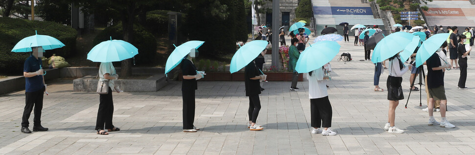 수도권에 사회적 거리두기 4단계가 시행된 12일 오후 인천시 남동구 구월동 한 선별검사소에서 시민들이 양산을 들고 검사를 기다리고 있다. 연합뉴스