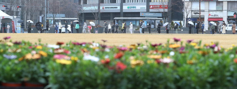 봄비가 내린 13일 오전 서울광장 임시선별검사소에서 시민들이 우산을 쓰고 코로나 검사를 기다리고 있다. 신소영 기자 viator@hani.co.kr