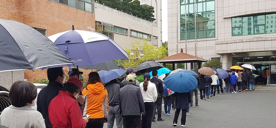 11일 오후 울산시 남구 옥동 울산보훈지청 사전투표소에서 줄을 길게 늘어선 유권자들이 갑작스럽게 비가 내리자 우산을 꺼내 쓰거나 그대로 비를 맞으면서 투표 순서를 기다리고 있다. 연합뉴스