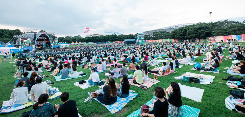 지난해 6월26일 서울 송파구 올림픽공원 88잔디마당에서 열린 ‘뷰티풀 민트 라이프 2021’에서 관객이 돗자리를 깔 수 있는 ‘지정 피크닉존’에서 관객이 공연을 보고 있다. 민트페이퍼 제공