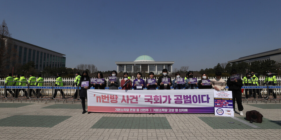 기본소득당 신민주 은평(을)·신지혜 고양(정) 예비후보가 23일 오전 국회 앞에서 연 `엔(n)번방 사건 국회가 공범이다' 기자회견에서 참가자들이 국회를 규탄하는 손팻말을 들고 있다. 이정아 기자