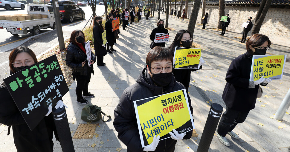 서울시민사회네트워크, 서울시마을법인협의회, 서울마을활동가연대, 서울마을자치센터연합 활동가들이 ‘서울의 민주주의가 죽었다. 과거로 퇴행하는 오세훈 서울시정을 바로 잡는 풀뿌리 지역사회 시민행동과 공동기자회견’을 열기 위해 손팻말을 들고 이동하고 있다. 김혜윤 기자