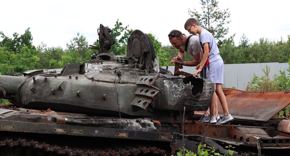 우크라이나 드미트리우카 지역 고속도로에 놓인 러시아군의 장갑차와 탱크 등을 부차에서 올하 소키르코의 남편과 아들이 살펴보고 있다. 드미트리우카/김혜윤 기자