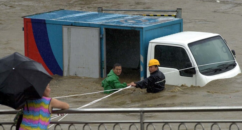 강원도 강릉지역에 2002년 8월31일 태풍 ‘루사’로 인해 내린 폭우로 남대천 물이 넘쳐 둔치에 주차해 있던 차량들이 떠내려가자 주민들이 밧줄로 묶고 있다. 연합뉴스