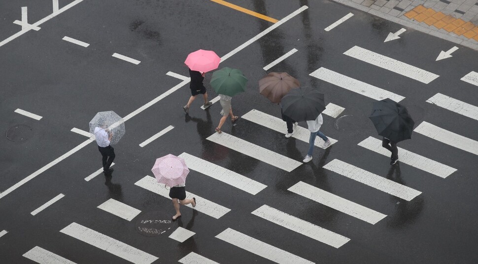 본격적인 여름 장마가 시작된 24일 오전 서울 종로구 경복궁 옆 건널목에서 시민들이 우산을 쓴 채 걸어가고 있다. 백소아 기자