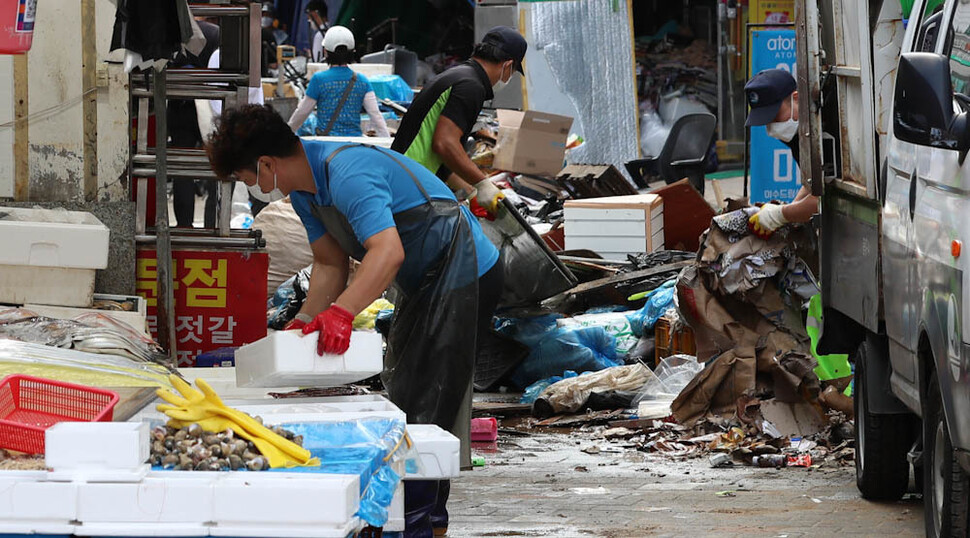 중부지방에 내린 기록적인 폭우에 잠겼던 서울 동작구 사당동 남성사계시장에서 10일 오전 공무원 등이 물에 젖어 못쓰게 된 물건들을 치우는 동안 상인이 점포의 물건을 정리하는 등 장사 준비를 하고 있다. 김정효 기자 hyopd@hani.co.kr