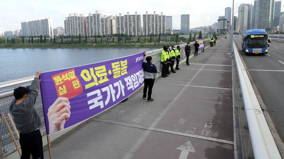 노동절을 닷새 앞둔 26일 오전 민주노총 조합원들이 서울 한강대교 위에서 의료·돌봄 국가책임제 등 요구사항을 쓴 펼침막을 들고 출근길 시민들을 향해 선전전을 하고 있다. 김정효 기자