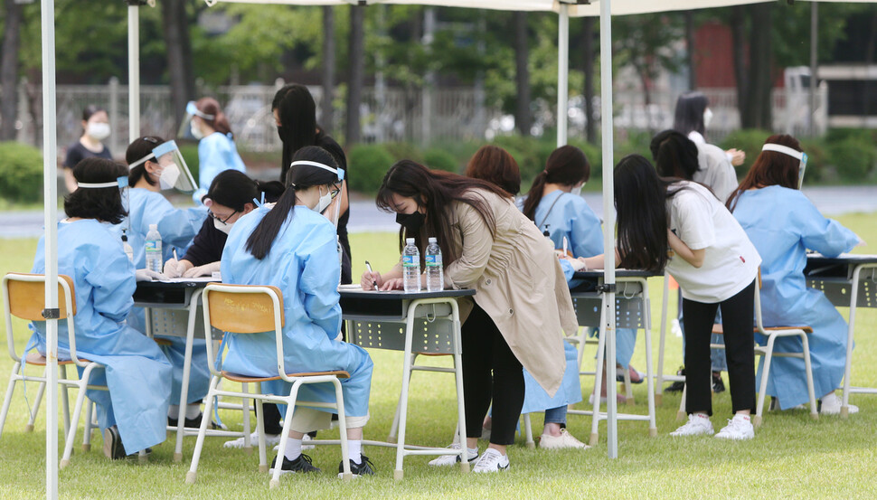 지난 6일 오전 인천시 연수구 인천뷰티예술고 운동장에 설치된 선별 진료소에서 학생들이 검체 검사 전 문진표를 작성하고 있다. 연합뉴스