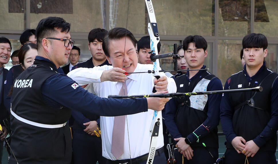 윤석열 대통령이 14일 충북 진천선수촌 양궁장을 방문해 김우진 선수에게 도움을 받아 과녁을 겨누고 있다. 대통령실사진기자단