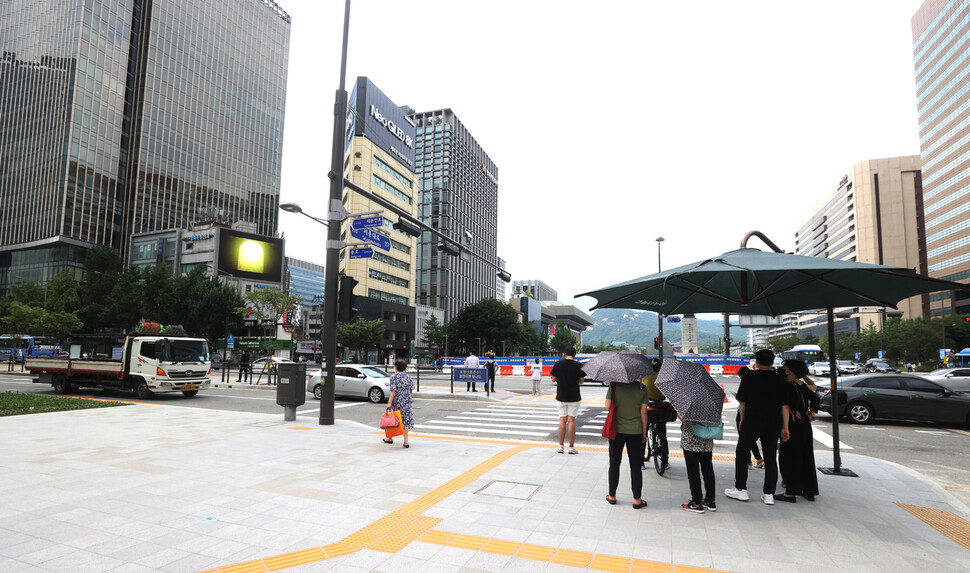 무더위가 계속된 15일 오후 서울 광화문역 사거리에서 시민들이 그늘 쉼터를 찾아 해를 피하며 건널목 신호를 기다리고 있다. 연합뉴스