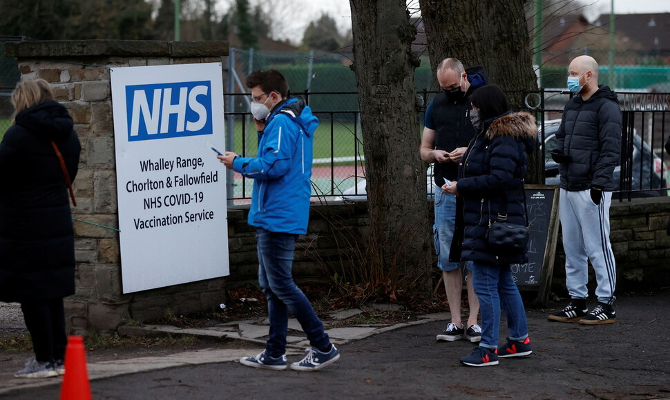 영국의 무상의료 국민보건서비스(NHS)는 보편적 기본서비스(UBS)의 전형적 형태다. 2021년 12월 맨체스터의 코로나바이러스 백신 센터에서 영국인들이 백신을 맞기 위해 줄을 서 기다리고 있다. REUTERS