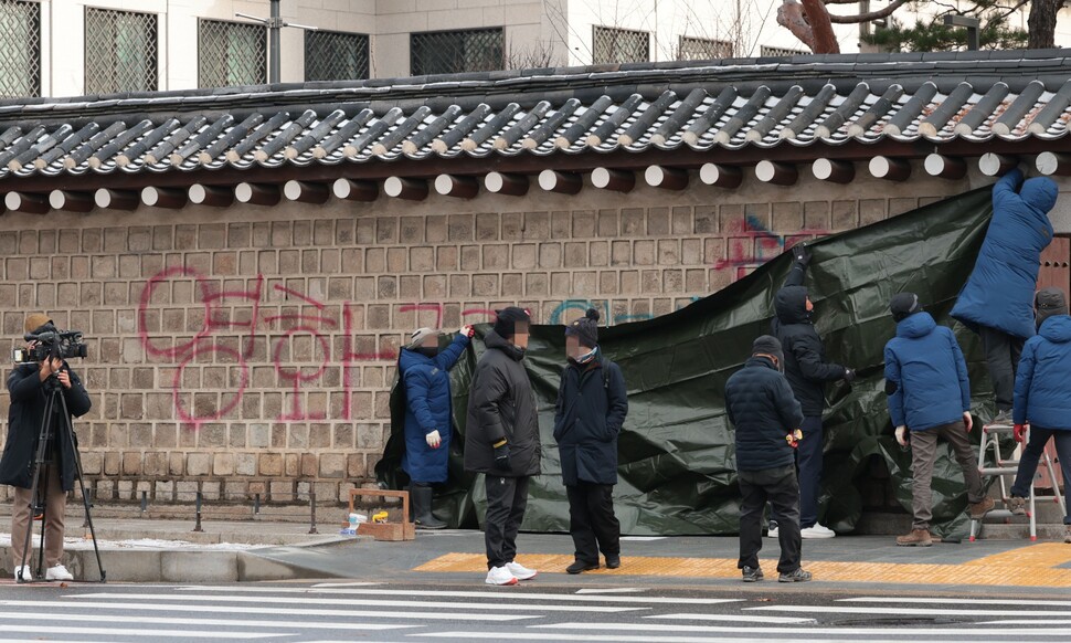 16일 오전 서울 종로구 경복궁에서 관계자들이 서쪽 담벼락에 누군가 스프레이로 낙서한 부분을 천막으로 가리고 있다. 연합뉴스