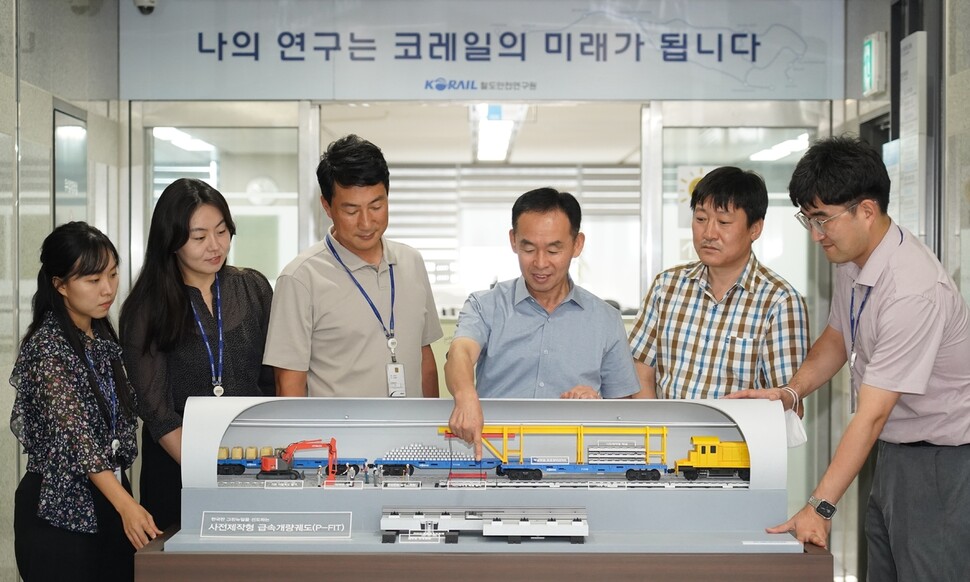 윤임수 코레일 기술안전연구처장(왼쪽 넷째)이 지난달 16일 철도안전연구원 연구원들과 사전제작 콘크리트 궤도 모형과 급속시공 전용 장비 모형에 대한 의견을 나누고 있다. 코레일 제공