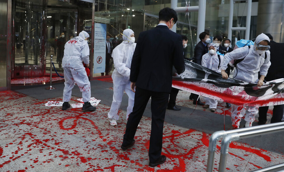 기후위기 비상행동 활동가들이 12일 오전 서울 강남구 포스코센터 앞에서 ‘기후·노동·인권 악당 포스코 규탄대회’를 열고 건물에 빨간 물감을 뿌리는 행위극을 하고 있다. 김혜윤 기자