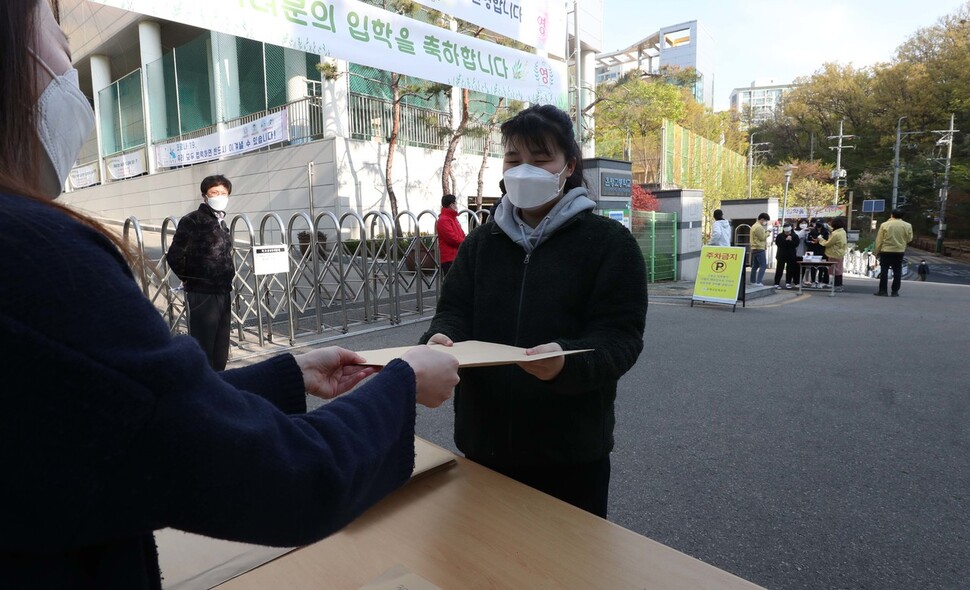 조현진 학생이 교문 앞에서 시험지를 받고 있다. 박종식 기자