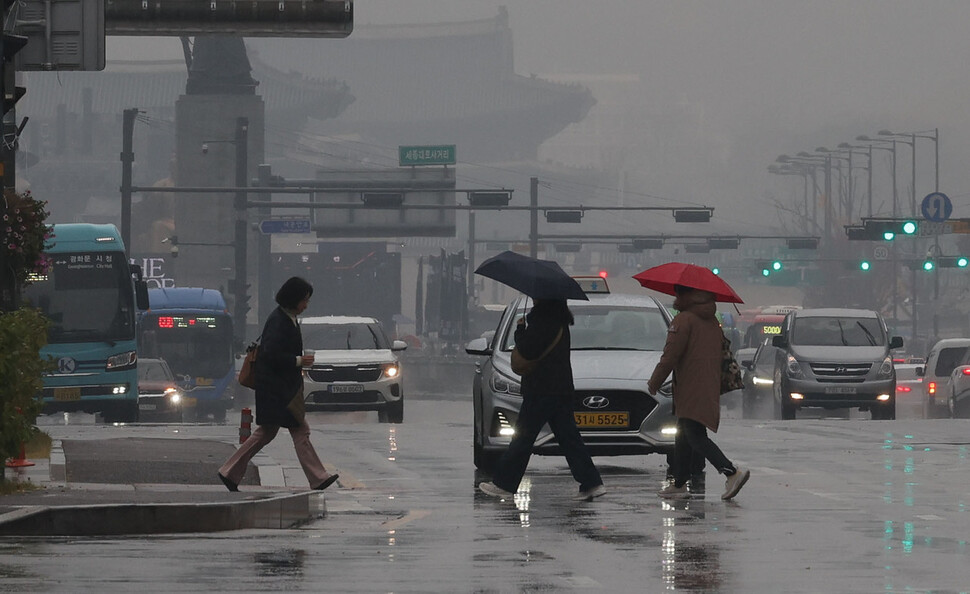 겨울을 재촉하는 비가 내린 16일 오전 서울 중구 세종대로에서 우산을 쓴 채 길을 건너는 시민들 뒤로 뿌연 시야가 깔려 있다. 이날 서울 등 서쪽 대부분과 경북 지역의 초미세먼지 농도는 ‘나쁨’ 수준을 보였다. 백소아 기자