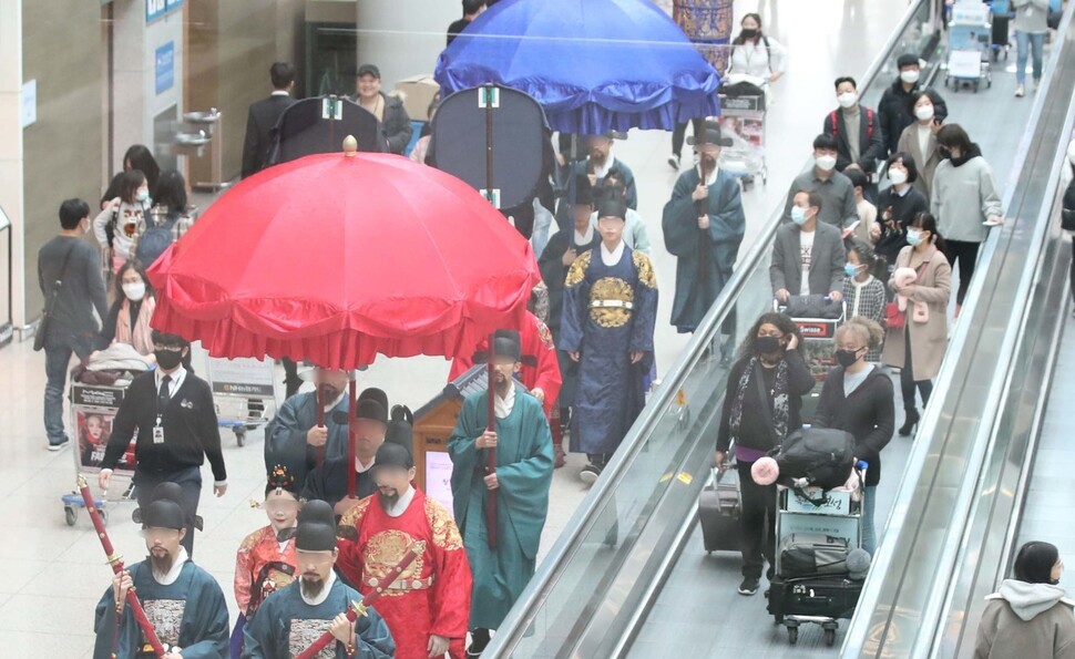 신종 코로나바이러스 감염증이 퍼지고 있는 가운데 29일 오전 인천국제공항 제1터미널 면세점에서 마스크를 하지 않은 임시직 노동자들이 어가행렬 행사를 하고 있다. 이들 옆으로 마스크를 한 관광객들이 재연 공연을 바라보며 지나가고 있다. 인천공항/백소아 기자 thanks@hani.co.kr