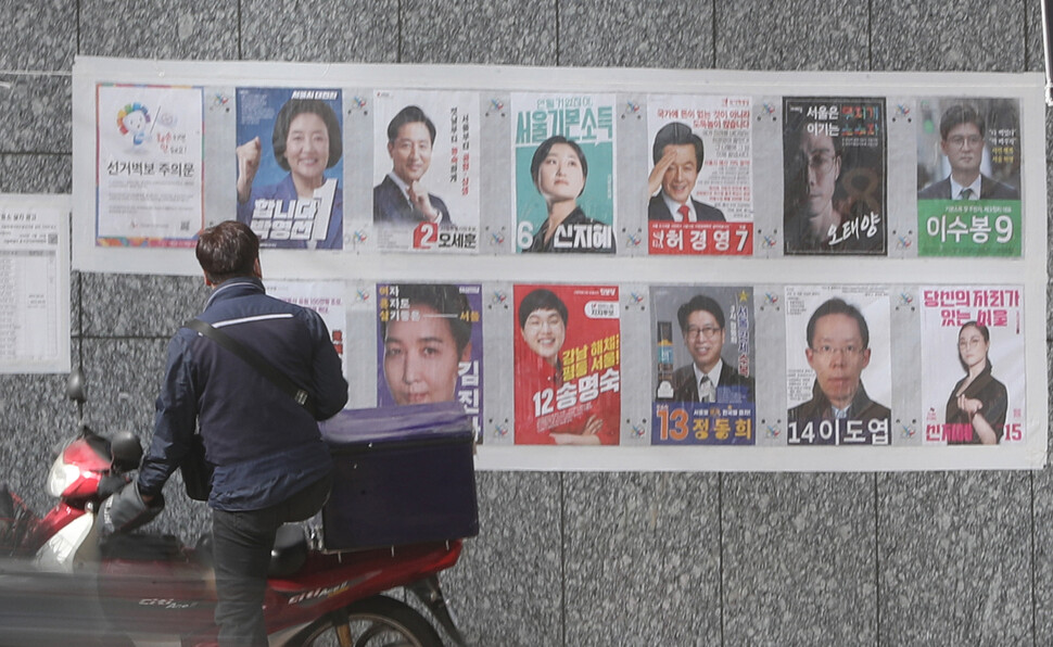 4.7 서울시장 보궐선거 사전투표를 나흘 앞둔 29일 오전 시민들이 서울 중구 명동 입구에 부착된 선거벽보 앞을 지나고 있다. 연합뉴스