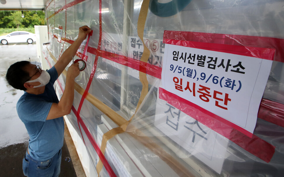 태풍 힌남노가 북상 중인 5일 광주 서구 5·18민주화운동교육관에 마련된 코로나19 임시선별검사소에서 의료진이 태풍에 대비한 안전조치를 한 뒤 일시중단 안내문을 붙이고 있다. 연합뉴스