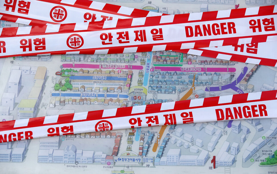 26일 오전 코로나19 집단감염 발생으로 폐쇄된 서울 중구 중부시장 입구에 설치된 시장 안내판 위로 출입을 통제하는 안전선이 설치돼 있다.  연합뉴스