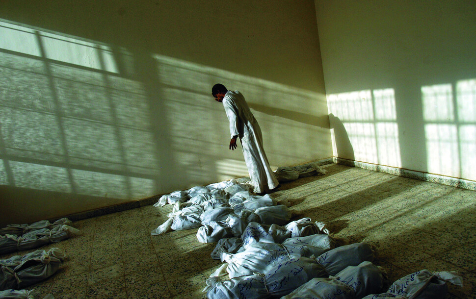 후세인 정권 몰락 후 이라크 전역에 있는 집단 매장지에서 정권에 의해 살해당한 수천 구의 유해가 발견됐다. 바드다드 남쪽 매장지에서 수습된 유해 사이를 걸어가던 남성이 벽에 기대어 서 있다. 2003년. 5월 29일. 사진 린지 아다리오, 문학동네 제공