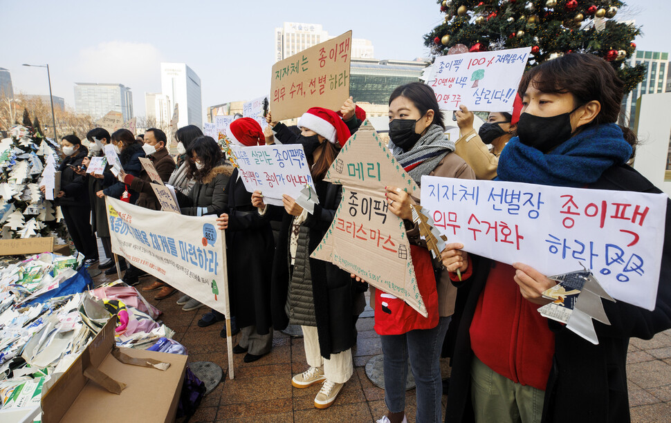 21일 서울시청 잔디광장에서 열린 종이팩 재활용 체계 마련을 촉구하는 시민들의 ‘메리 종이팩 크리스마스’ 기자회견에서 서울환경연합 회원들이 관련 내용이 적힌 손피켓을 들고 있다. 연합뉴스