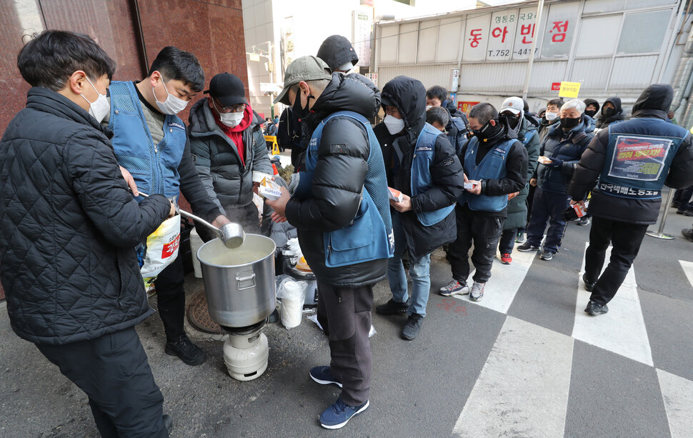 18일 오전 서울 중구 씨제이대한통운 본사 점거농성장 밖에서 종교시민사회단체 공동대책위 발족 기자회견이 끝난 뒤 농성 중인 조합원들이 점심으로 떡국을 받아들고 있다. 김태형 기자