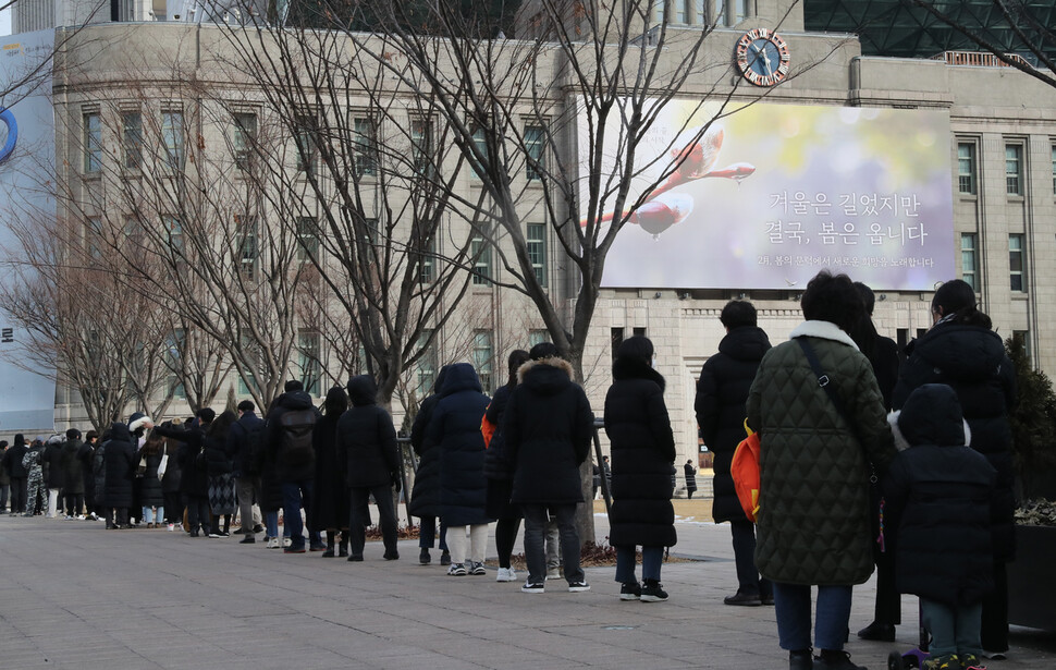 7일 오전 서울 중구 서울광장 임시선별검사소에서 시민들이 신속항원검사를 받기 위해 길게 줄 서 있다. 서울도서관 꿈새김판에는 ‘겨울은 길었지만 결국, 봄은 옵니다’ 문구를 내걸려 있다. 김태형 기자