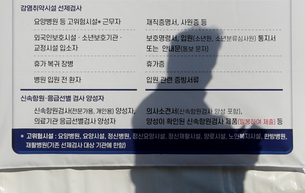 10일 오전 서울 송파구 올림픽공원 선별진료소 천막에 걸린 유전자증폭검사 우선순위 대상 안내문 위로 차례를 기다리는 한 시민의 그림자가 비치고 있다. 신소영 기자