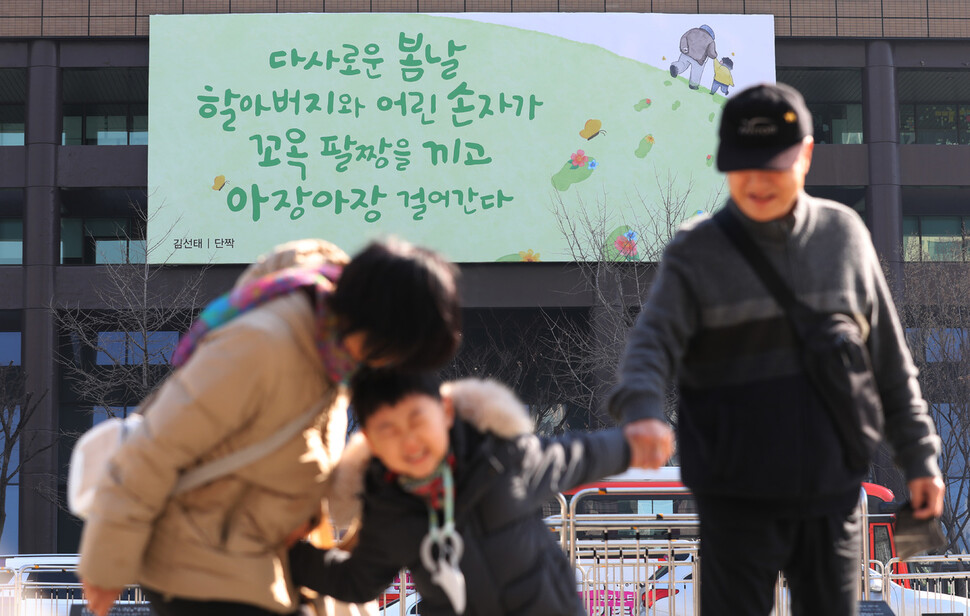 27일 오전 광화문 교보생명빌딩에 걸려있는 광화문글판 봄편 앞으로 한 어린이가 할아버지, 할머니의 손을 잡고 걷고 있다. 김혜윤 기자 unique@hani.co.kr