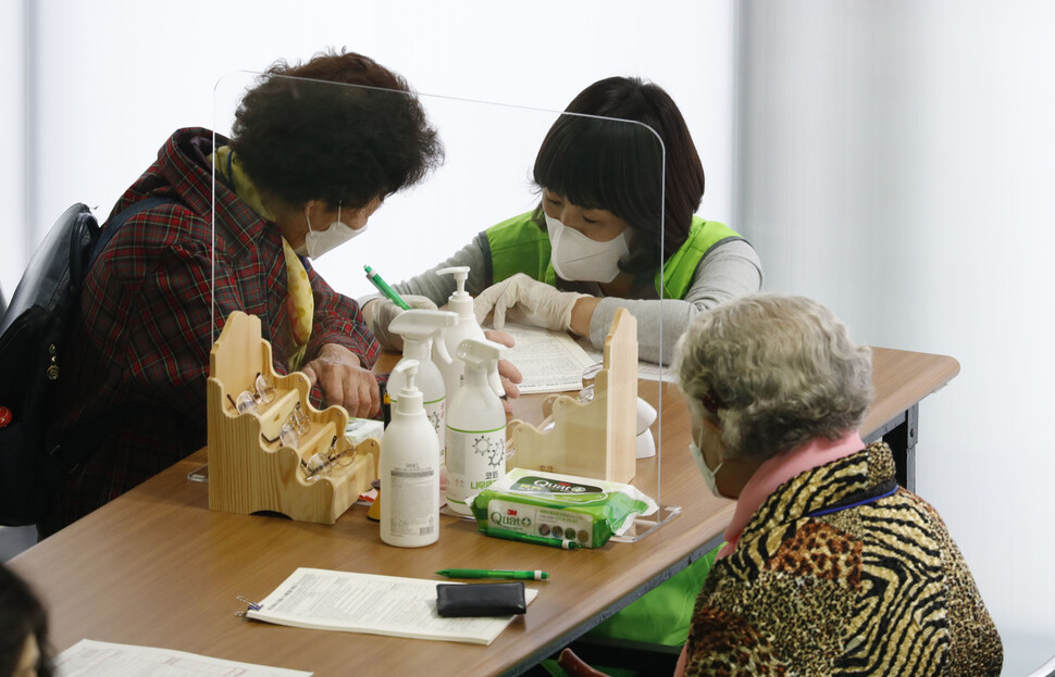 15일 오전 서울 서대문구 북아현문화체육센터에 마련된 코로나19 예방접종센터에서 한 직원이 어르신의 예진표 작성을 돕고 있다. 김혜윤 기자