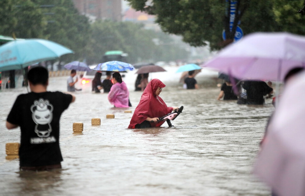 20일 중국 허난성 정저우에 폭우가 내려 잠긴 도로를 시민들이 지나가고 있다. 정저우/EPA 연합뉴스