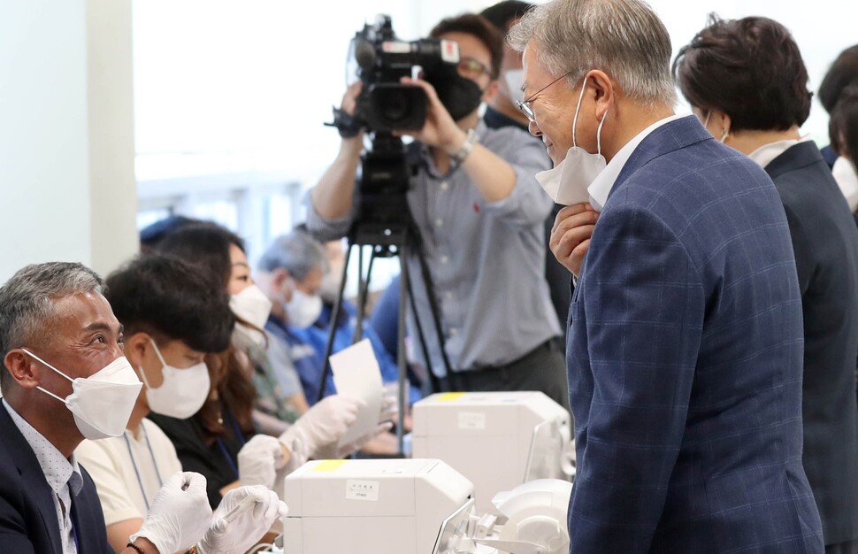 문재인 전 대통령이 27일 오전 경남 양산시 하북면주민자치센터에 마련된 사전투표소를 찾아 투표 전 마스크를 벗어 신원 확인을 하고 있다. 연합뉴스