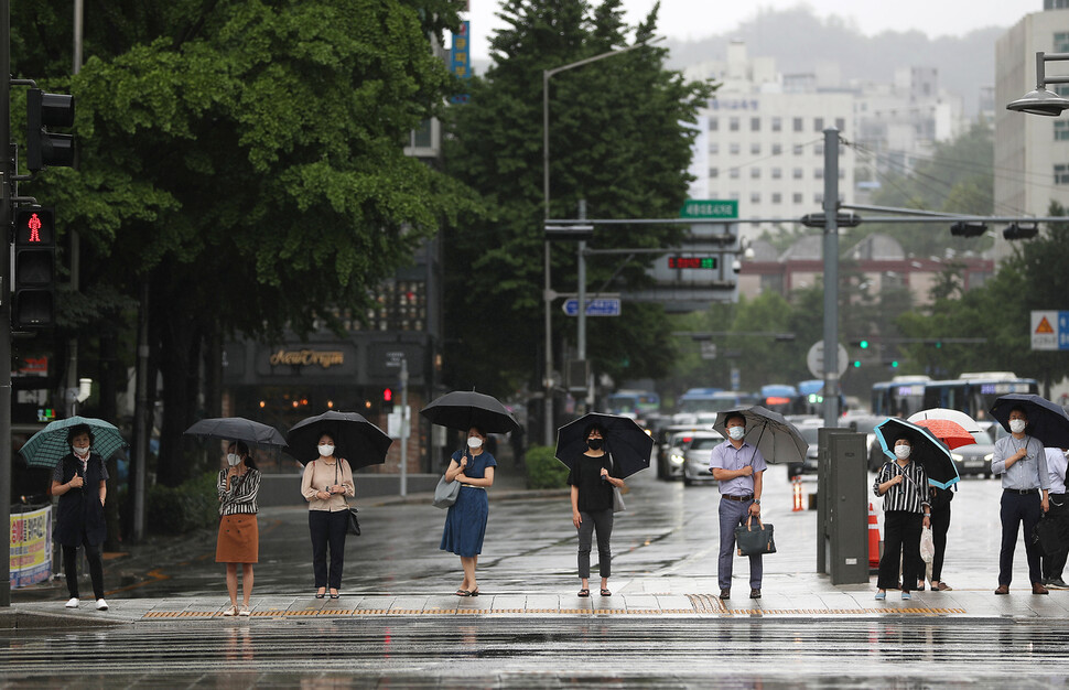 30일 오전 광화문네거리 횡단보도에서 우산을 쓴 출근길 시민들이 거리를 두고 서서 신호를 기다리고 있다. 연합뉴스