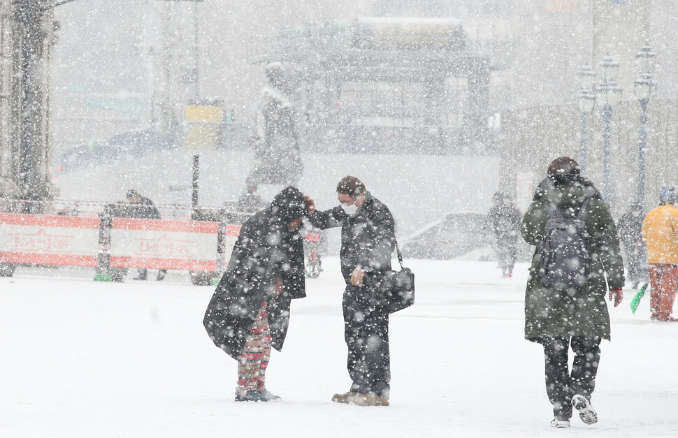 갑작스럽게 많은 눈이 내린 18일 오전 서울 중구 서울역 앞에서 한 시민이 거리 노숙인에게 자신의 방한점퍼, 장갑을 벗어주고 있다. 백소아 기자 thanks@hani.co.kr
