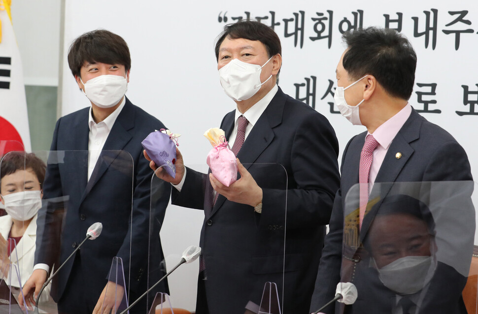 국민의힘 윤석열 대선후보(가운데)가 8일 오전 서울 여의도 국회에서 열린 최고위원회의에서 이준석 대표(왼쪽)로부터 비단주머니를 받고 발언하고 있다. 국회사진기자단 국민의힘 윤석열 대선후보(가운데)가 8일 오전 서울 여의도 국회에서 열린 최고위원회의에서 이준석 대표(왼쪽)로부터 비단주머니를 받고 발언하고 있다. 국회사진기자단