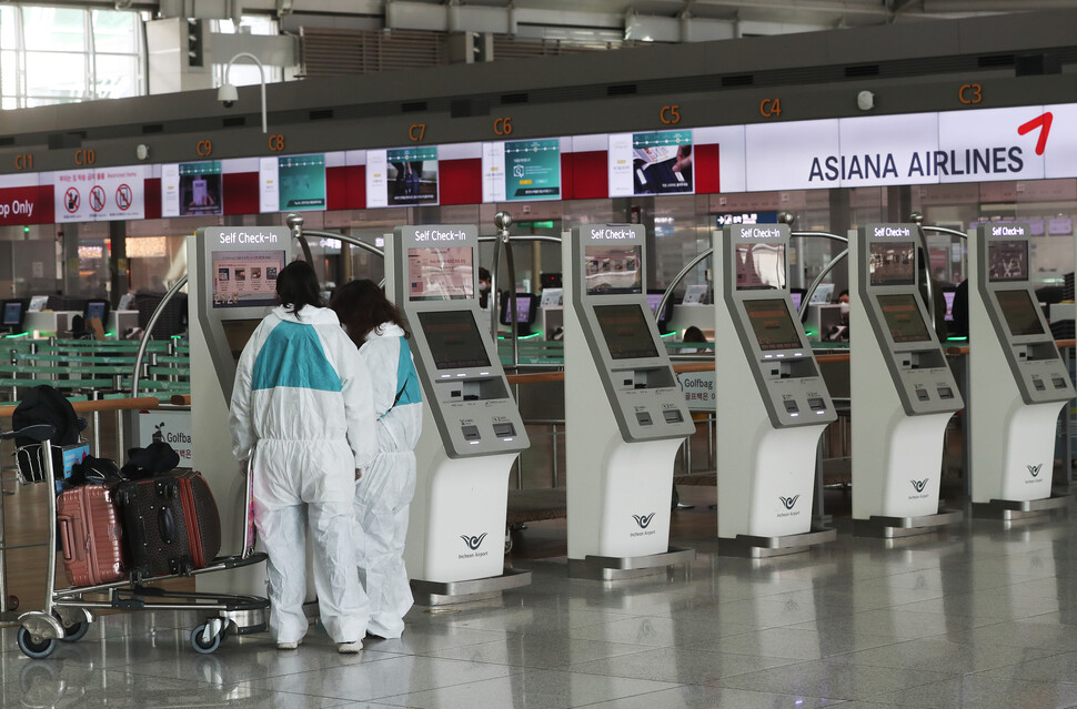 베트남 정부가 한국발 여객기의 하노이 공항 착륙을 임시 불허함에 따라 29일 오전 인천국제공항을 출발한 아시아나항공 여객기가 인천으로 회항했다. 이날 인천공항 출발층에 보호복을 입은 이용객들이 체크인을 하고 있다. 연합뉴스