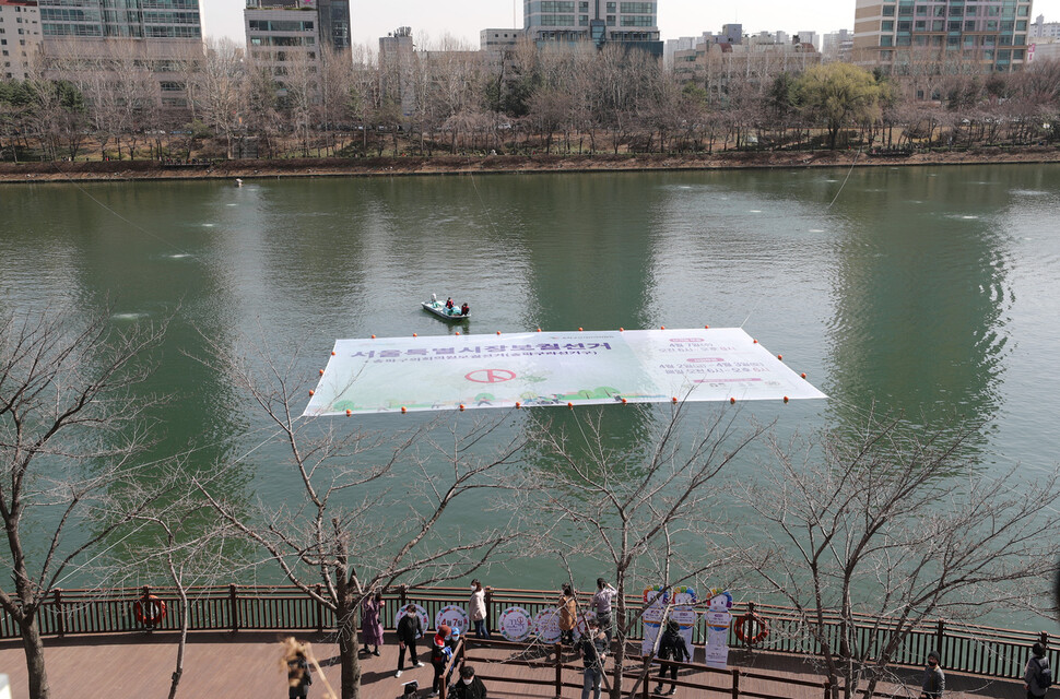 4.7 재보궐선거를 앞두고 서울시 송파구선거관리위원회 관계자들이 17일 오후 서울 송파구 석촌호수에서 투표참여를 홍보하는 커다란 걸게그림을 부표를 이용해 띄우고 있다. 이종근 선임기자 root2@hani.co.kr