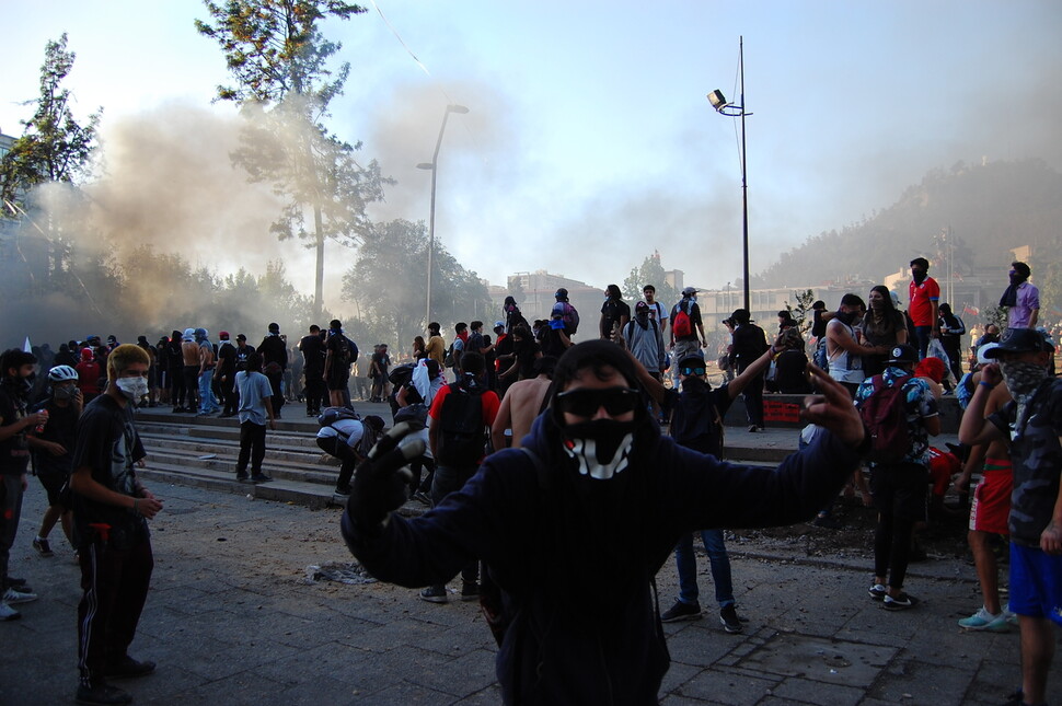 28일(현지시각) 칠레 수도 산티아고의 이탈리아광장에서 얼굴을 가린 시위대가 반정부 구호를 외치며 시위를 하고 있다.